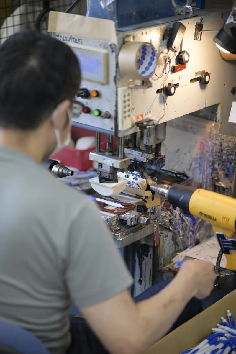 印刷機を調整するマスク姿の職人